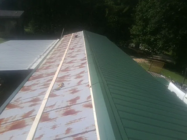 Old rusted panels beside newly installed green metal roofing — Wind Damage Roof Repair by Roofing Brothers in Takoma Park