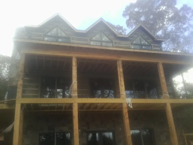 Dormers and porch framing on a large log home under construction — Roof Coating work by our crew in Takoma Park