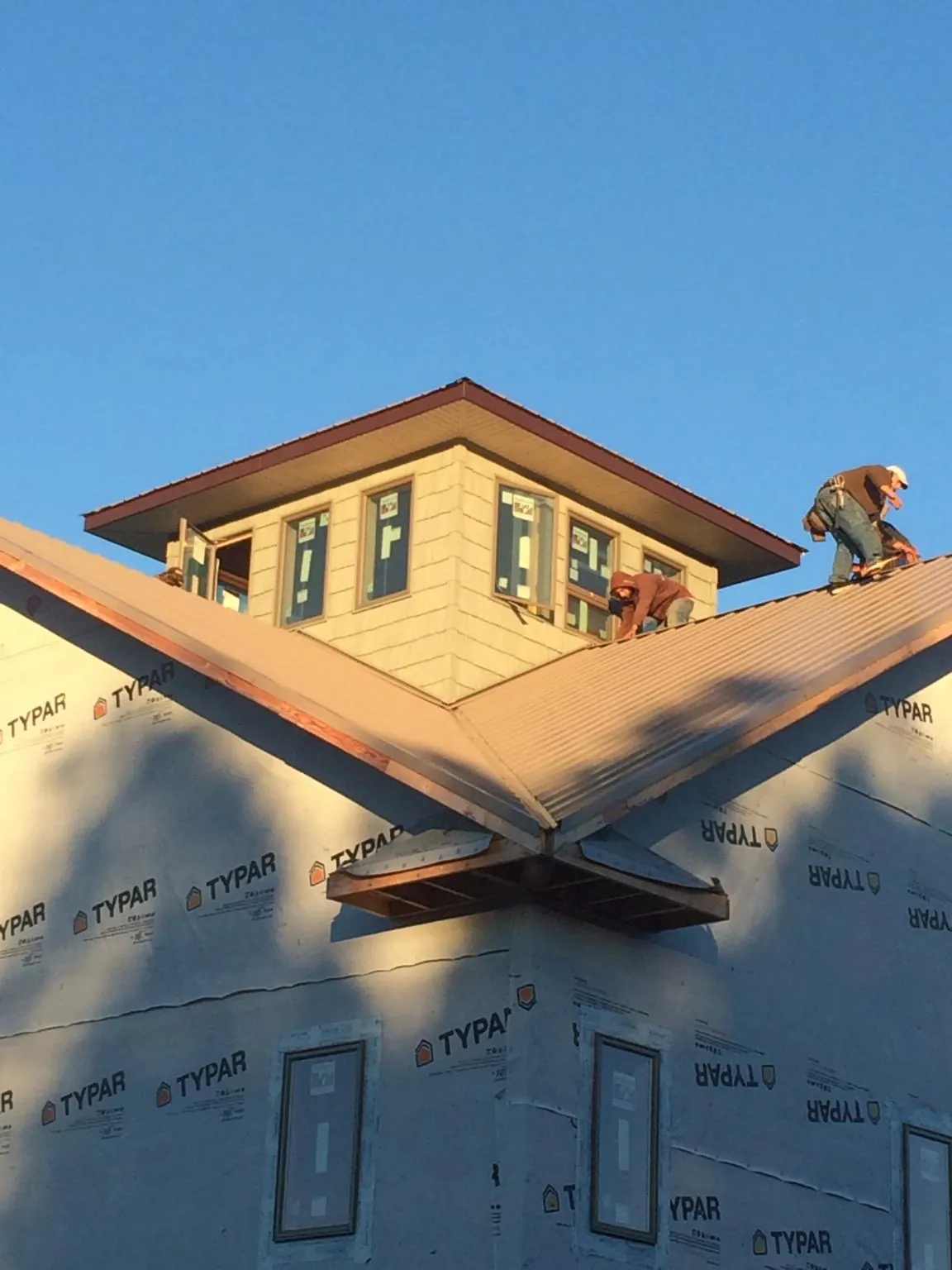 Roofers working around a rooftop cupola on a new metal roof at sunset — Roof Waterproofing in Takoma Park by Roofing Brothers